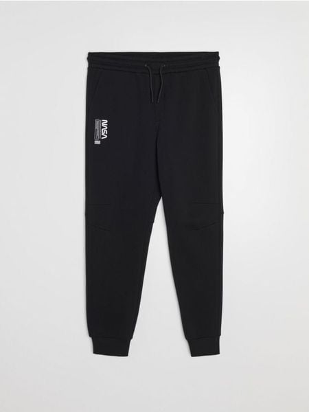 Spodnie dresowe tapered fit NASA - czarny. Czarne spodnie sportowe męskie Sinsay, z dresówki. Za 59.99 zł.