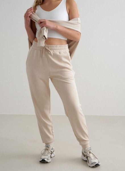 Damskie spodnie dresowe regular fit, ściągacze Comfy Modal beżowe. Białe spodnie sportowe damskie Aim'n, xl, z dresówki, na fitness i siłownię. Za 339.00 zł.