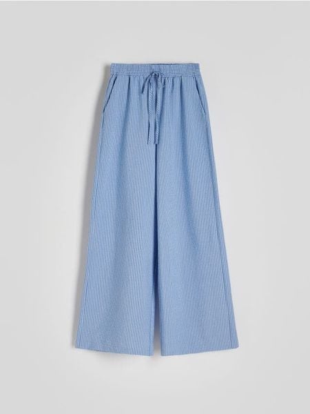Szerokie spodnie w stylu piżamowym - niebieski. Niebieskie spodnie materiałowe damskie Reserved, bez wzorów, z bawełny. W wyprzedaży za 49.99 zł.