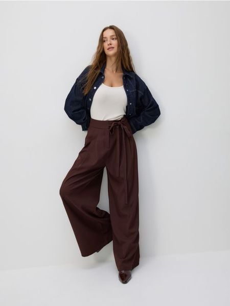 Spodnie z wiązaniem - ciemnobrązowy. Brązowe spodnie materiałowe damskie Reserved, bez wzorów, z tkaniny. Za 139.99 zł.