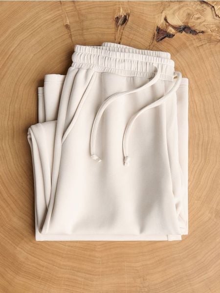 Spodnie z szeroką nogawką - beżowy. Brązowe spodnie materiałowe damskie Reserved, bez wzorów, z dzianiny. Za 119.99 zł.