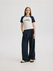 Bawełniany t-shirt z aplikacją - granatowy. Niebieskie koszulki dziewczęce Reserved, z aplikacjami, z bawełny, bez ramiączek. W wyprzedaży za 19.99 zł.