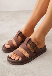 Brązowe Klapki Ozdobione Geometrycznymi Paskami i Metaliczną Klamrą Hossei. Brązowe klapki damskie Renee, bez wzorów, bez obcasa, na płaskiej podeszwie. Za 79.99 zł.