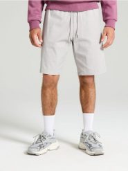 Szorty jogger - kremowy. Białe szorty męskie Sinsay, z jeansu, bez kołnierzyka. W wyprzedaży za 29.99 zł.