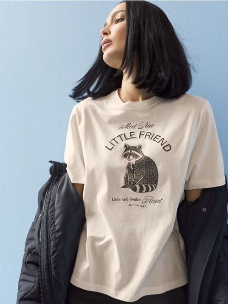 Bawełniana koszulka z motywem szopa pracza - kremowy. Białe t-shirty damskie Sinsay, l, bez wzorów, z bawełny, bez kołnierzyka. Za 19.99 zł.