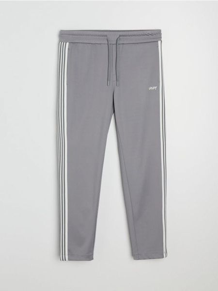 Spodnie dresowe z ozdobnymi taśmami po boku - szary. Szare spodnie sportowe męskie Sinsay, z dresówki. Za 59.99 zł.