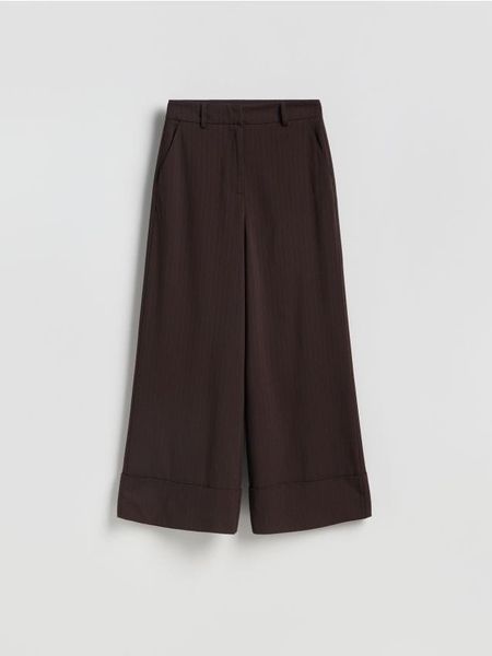 Luźne spodnie - ciemnobrązowy. Brązowe spodnie materiałowe damskie Reserved, bez wzorów, z tkaniny. Za 129.99 zł.