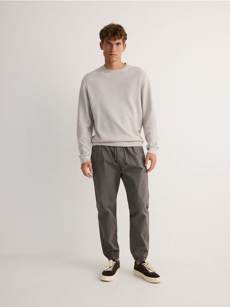 Spodnie jogger slim - szary. Szare spodnie materiałowe męskie Reserved, bez wzorów, z bawełny. W wyprzedaży za 65.99 zł.