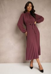 Fioletowa Sukienka Plisowana o Rozkloszowanym Kroju ze Stójką Gumką i Paskiem Zinnoritta. Fioletowe sukienki damskie Renee, na co dzień, uniwersalny, bez wzorów, eleganckie, bez kołnierzyka, bez ramiączek, maxi, kopertowe. W wyprzedaży za 76.99 zł.