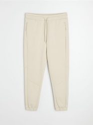 Spodnie tapered fit Active - kremowy. Białe spodnie sportowe męskie Sinsay. Za 59.99 zł.