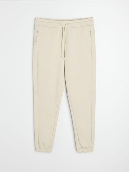 Spodnie tapered fit Active - kremowy. Białe spodnie sportowe męskie Sinsay. Za 59.99 zł.