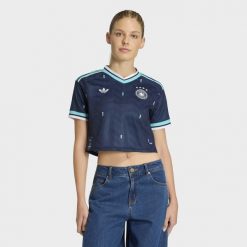 Koszulka wyjazdowa o skróconym fasonie Niemcy 26. Niebieskie bluzki damskie Adidas, bez wzorów, bez kołnierzyka. Za 369.00 zł.