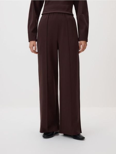 Spodnie z szeroką nogawką - ciemnobrązowy. Brązowe spodnie materiałowe damskie Reserved, bez wzorów, z bawełny. Za 99.99 zł.