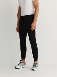 Spodnie jogger slim - czarny. Czarne spodnie materiałowe męskie Reserved, bez wzorów, z bawełny. W wyprzedaży za 69.99 zł.