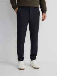 Spodnie jogger slim - czarny. Czarne spodnie materiałowe męskie Reserved, bez wzorów, z tkaniny. W wyprzedaży za 69.99 zł.