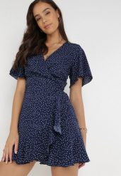 Granatowa Sukienka Devizo. Niebieskie sukienki damskie Born2be, s, bez wzorów, z materiału, bez kołnierzyka, bez ramiączek, mini, kopertowe. W wyprzedaży za 51.99 zł.