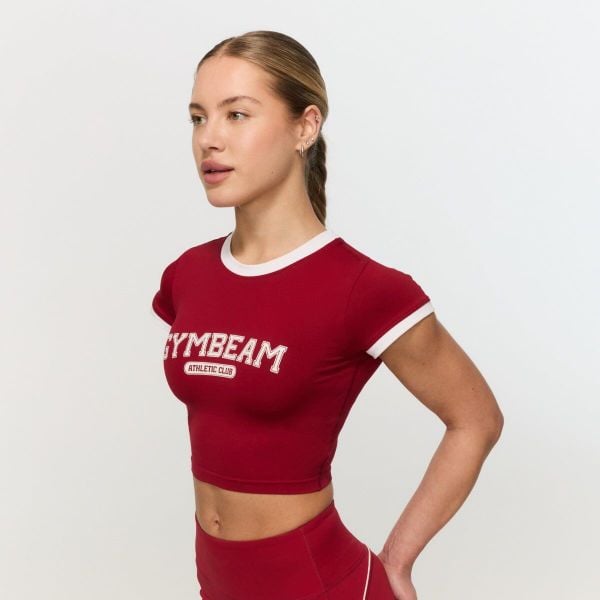 Koszulka damska fitness slim czerwona Varsity. Czerwone bluzki sportowe damskie GYMBEAM, l, bez wzorów, z materiału, bez ramiączek. Za 88.90 zł.