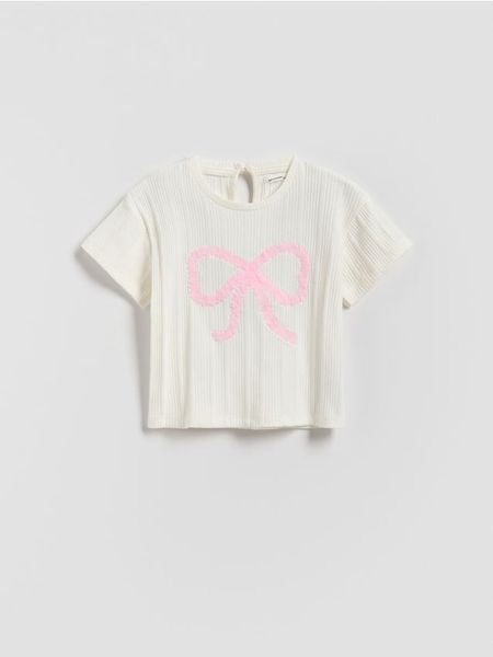 Bawełniany t-shirt z aplikacją - złamana biel. Koszulki dziewczęce Reserved, m, z aplikacjami, z bawełny, bez ramiączek. W wyprzedaży za 22.99 zł.
