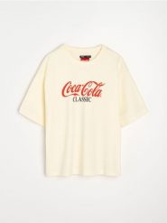 Bawełniana koszulka z nadrukiem na plecach Coca-Cola - żółty. Żółte t-shirty damskie Sinsay, l, bez wzorów, z bawełny, bez kołnierzyka. Za 39.99 zł.