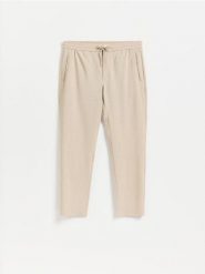 Spodnie jogger - beżowy. Brązowe spodnie materiałowe męskie Reserved, bez wzorów, z tkaniny. Za 149.99 zł.