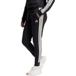 Spodnie damskie adidas Essentials 3-Stripes Fleece Slim. Białe spodnie sportowe damskie Adidas, xl, z bawełny, na fitness i siłownię. Za 241.50 zł.