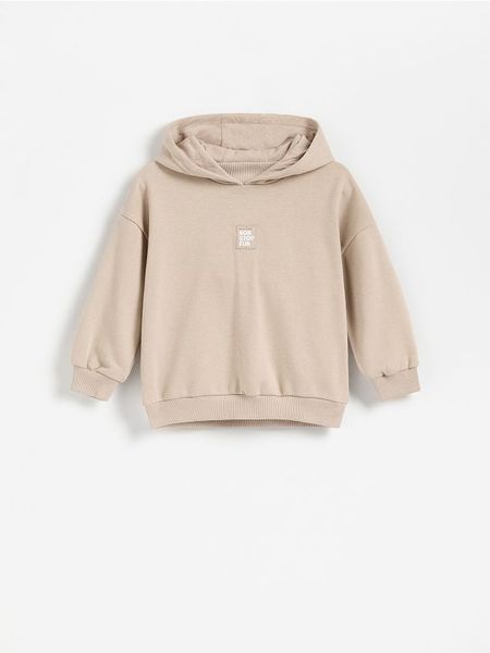 Bawełniana bluza z kapturem - kremowy. Białe bluzy i bluzki niemowlęce Reserved, bez wzorów, z bawełny, bez ramiączek, z kapturem. Za 49.99 zł.