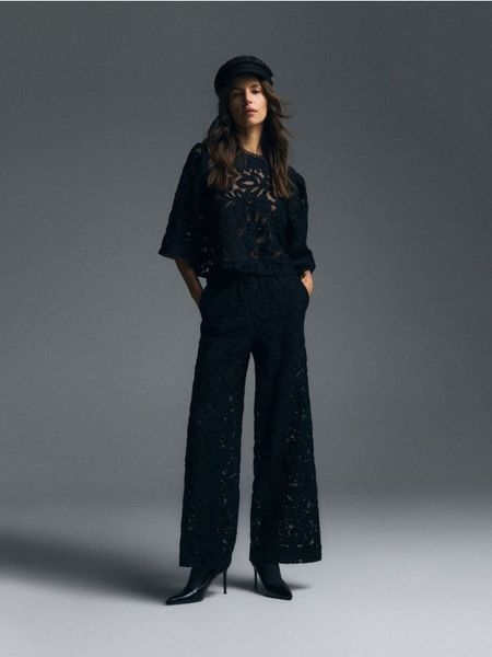 Spodnie ze strukturalnej tkaniny - czarny. Czarne spodnie materiałowe damskie Reserved, bez wzorów, z bawełny. W wyprzedaży za 69.99 zł.