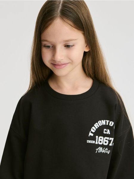 Bawełniana koszulka z nadrukiem - czarny. Czarne koszulki dziewczęce Reserved, bez wzorów, z bawełny, bez ramiączek. Za 49.99 zł.