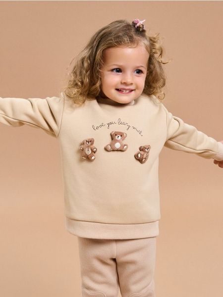 Ocieplana bluza crewneck - kremowy. Białe bluzy i bluzki niemowlęce Sinsay, bez wzorów, bez ramiączek, bez kaptura. W wyprzedaży za 13.99 zł.