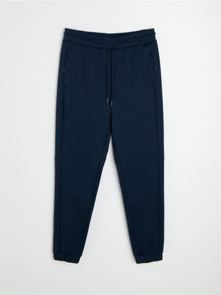 Spodnie tapered fit Active - granatowy. Niebieskie spodnie sportowe męskie Sinsay. Za 59.99 zł.