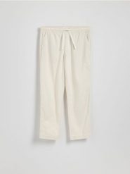 Bawełniane spodnie jogger - złamana biel. Spodnie materiałowe męskie Reserved, bez wzorów, z bawełny. Za 119.99 zł.