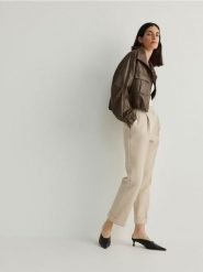 Spodnie z mankietami - beżowy. Brązowe spodnie materiałowe damskie Reserved, bez wzorów, z tkaniny. W wyprzedaży za 45.99 zł.