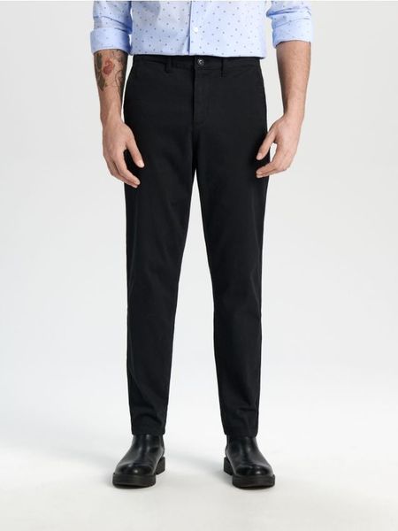 Spodnie chino - czarny. Czarne spodnie materiałowe męskie Sinsay, bez wzorów, z bawełny. Za 49.99 zł.