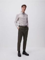 Spodnie chino carrot - ciemnozielony. Zielone spodnie materiałowe męskie Reserved, bez wzorów, z bawełny. W wyprzedaży za 69.99 zł.