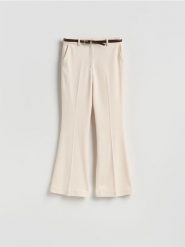 Spodnie flare z paskiem - złamana biel. Spodnie materiałowe damskie Reserved, bez wzorów, z tkaniny. Za 139.99 zł.