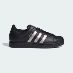 Buty SUPERSTAR MESSI. Czarne buty sportowe na co dzień damskie Adidas, bez wzorów, z gumy, do piłki nożnej, Adidas Superstar. Za 529.00 zł.