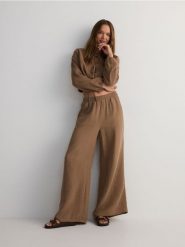 Muślinowe spodnie - brązowy. Brązowe spodnie materiałowe damskie Reserved, bez wzorów, z bawełny. W wyprzedaży za 89.99 zł.