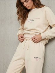 Spodnie regular jogger fleece z hafotwanym napisem NYC - kremowy. Białe spodnie materiałowe damskie Sinsay, bez wzorów. Za 39.99 zł.