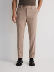 Spodnie chino slim z kantem - beżowy. Brązowe spodnie materiałowe męskie Reserved, bez wzorów, z tkaniny. W wyprzedaży za 79.99 zł.