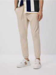 Spodnie jogger slim - kremowy. Białe spodnie materiałowe męskie Reserved, bez wzorów, z bawełny. Za 139.99 zł.