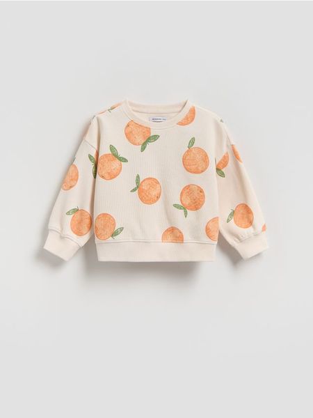 Luźna bluza z nadrukiem - kremowy. Białe bluzy i bluzki niemowlęce Reserved, bez wzorów, z bawełny, bez ramiączek, bez kaptura. Za 49.99 zł.
