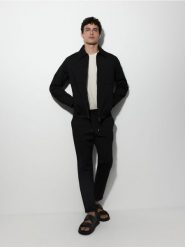 Spodnie chino slim - czarny. Czarne spodnie materiałowe męskie Reserved, bez wzorów, z dzianiny. W wyprzedaży za 79.99 zł.