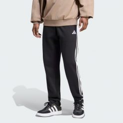 Spodnie Essentials z tkaniny frotté z 3 paskami i zwężanymi nogawkami. Białe spodnie materiałowe męskie Adidas, bez wzorów, z bawełny, klasyczne, z standardowym stanem. Za 219.00 zł.