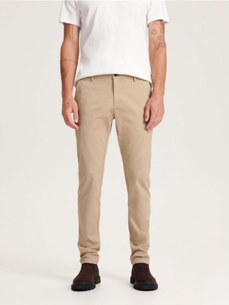 Spodnie chino slim fit - beżowy. Brązowe spodnie materiałowe męskie Reserved, bez wzorów, z bawełny. Za 159.99 zł.