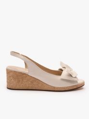 Kremowe sandały na koturnie z kokardą. Brązowe sandały damskie Ryłko, bez wzorów, ze skóry, bez obcasa, na koturnie. Za 399.99 zł.