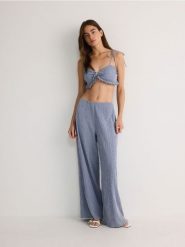 Spodnie ze strukturalnej tkaniny - granatowy. Niebieskie spodnie materiałowe damskie Reserved, bez wzorów, z bawełny. W wyprzedaży za 69.99 zł.