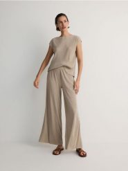 Plisowane spodnie wide leg - beżowy. Brązowe spodnie materiałowe damskie Reserved, bez wzorów, z dzianiny. W wyprzedaży za 49.99 zł.