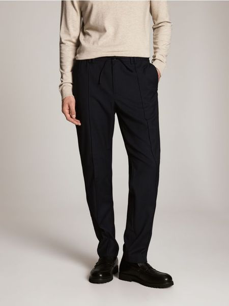 Spodnie slim fit z dodatkiem wełny - granatowy. Niebieskie spodnie materiałowe męskie Reserved, bez wzorów, z tkaniny. Za 249.99 zł.