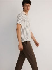 Spodnie chino slim z lnem - ciemnobrązowy. Brązowe spodnie materiałowe męskie Reserved, bez wzorów, z wiskozy. W wyprzedaży za 119.99 zł.