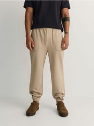 Spodnie jogger regular - beżowy. Brązowe spodnie materiałowe męskie Reserved, bez wzorów, z dzianiny. W wyprzedaży za 49.99 zł.